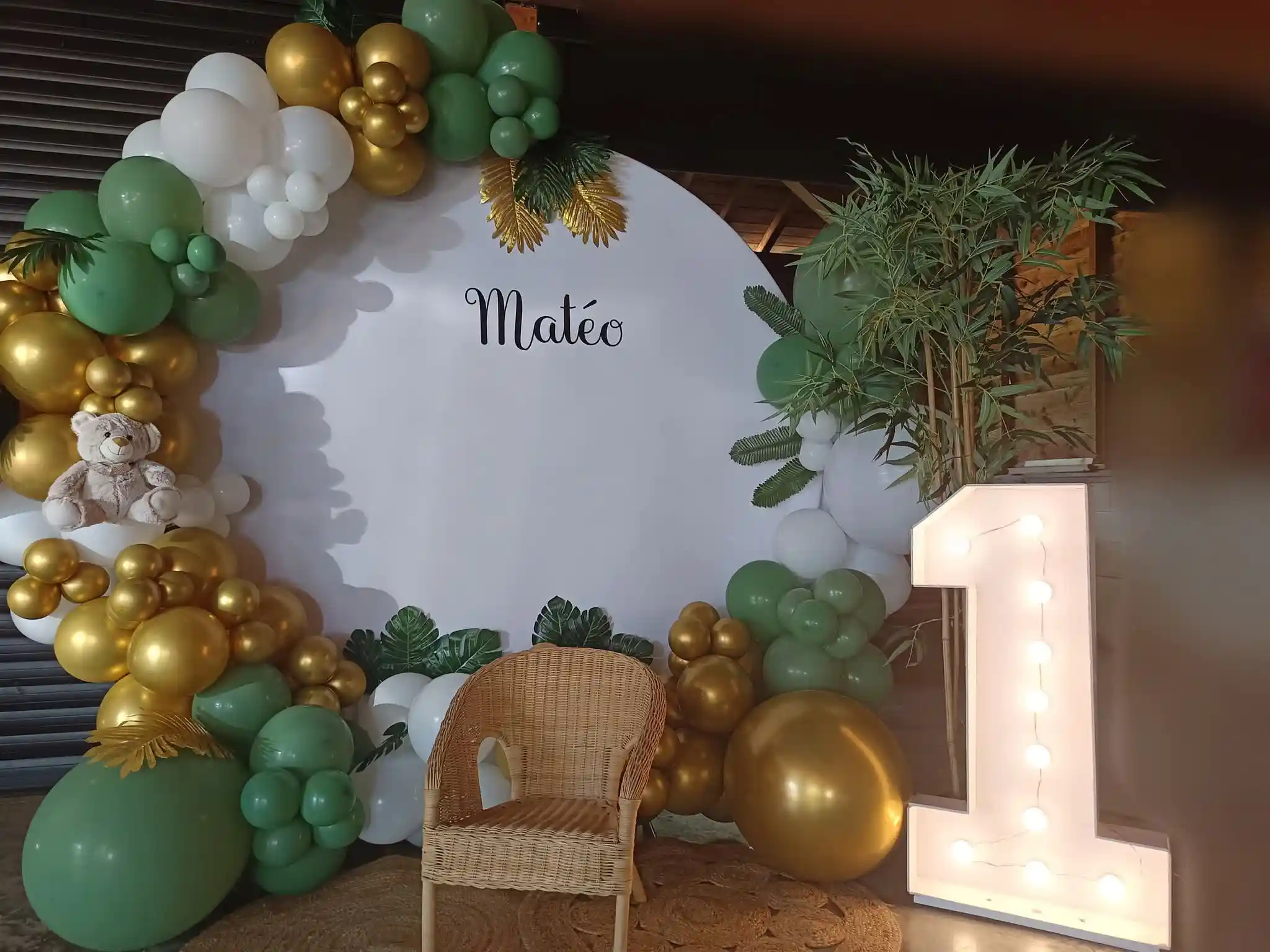 Arche de ballons vert, blanc et doré pour 1er anniversaire, panneau « Matéo », ours en peluche et grand chiffre lumineux 1.
